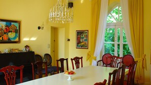 Une salle à manger avec une table blanche, des chaises en bois, un lustre et des œuvres d’art accrochées aux murs.