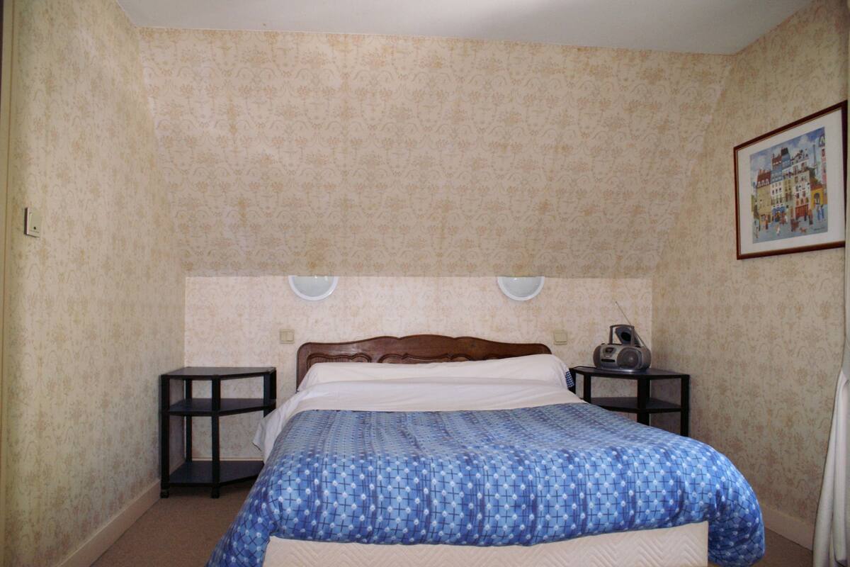 Un dormitorio con una cama, dos mesitas de noche y un radio fijado a la pared.
