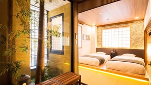 Une pièce de style japonais traditionnel, avec un sol recouvert de tatamis, une petite table en bois et une vue sur un lit avec un futon.