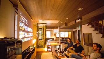 A modern living room with a flat-screen TV, a coffee table with bottles, and a sofa.