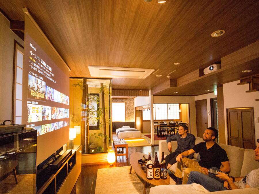 A modern living room with a flat-screen TV, a coffee table with bottles, and a sofa.