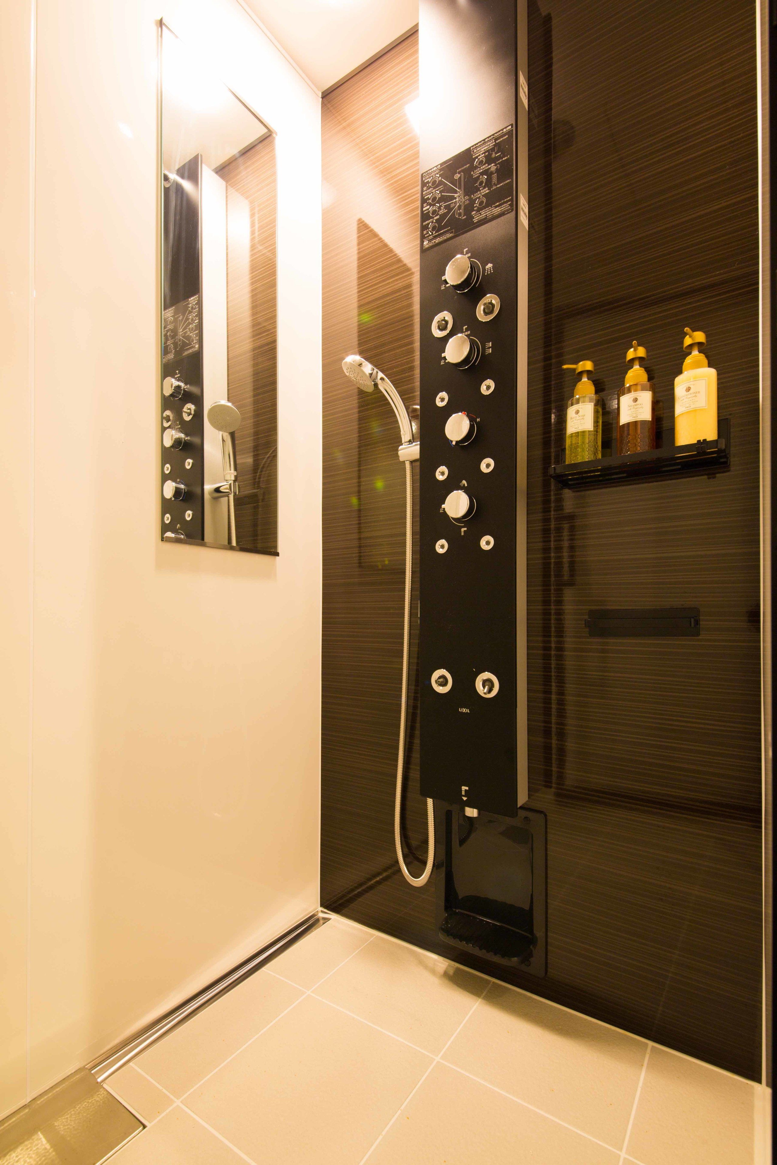 A modern bathroom with a glass-enclosed shower, a mirror, and a shelf with toiletries.
