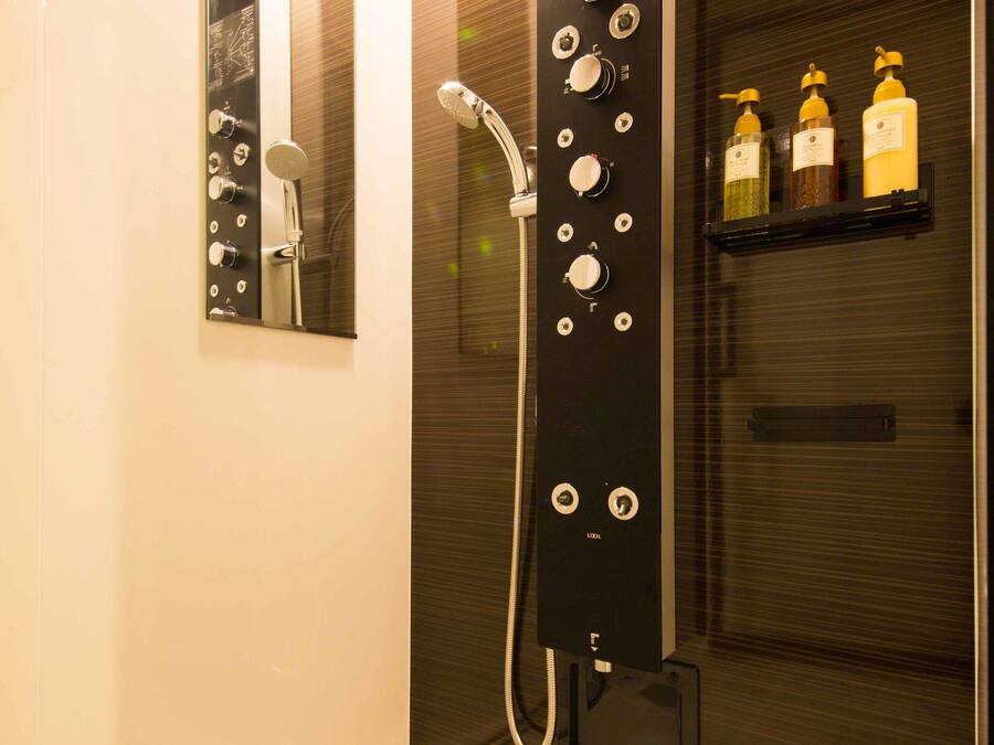 A modern bathroom with a glass-enclosed shower, a mirror, and a shelf with toiletries.
