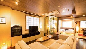 Une chambre d’hôtel moderne avec un plafond en bois, une télévision, un canapé et un coin repas comprenant une table et des chaises.