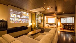 Un salon moderne doté d’un grand téléviseur à écran plat, de sièges confortables, d’un coin repas et d’une chambre avec une porte coulissante de style japonais traditionnel.