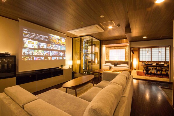 Una sala de estar moderna con un televisor de pantalla plana grande, un sofá, una mesa de centro y un comedor con una mesa y sillas.