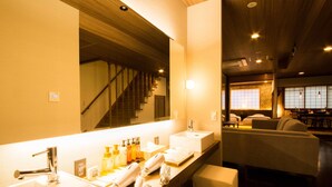 Une salle de bain d’hôtel avec deux lavabos, un miroir et un coin salon avec des chaises.