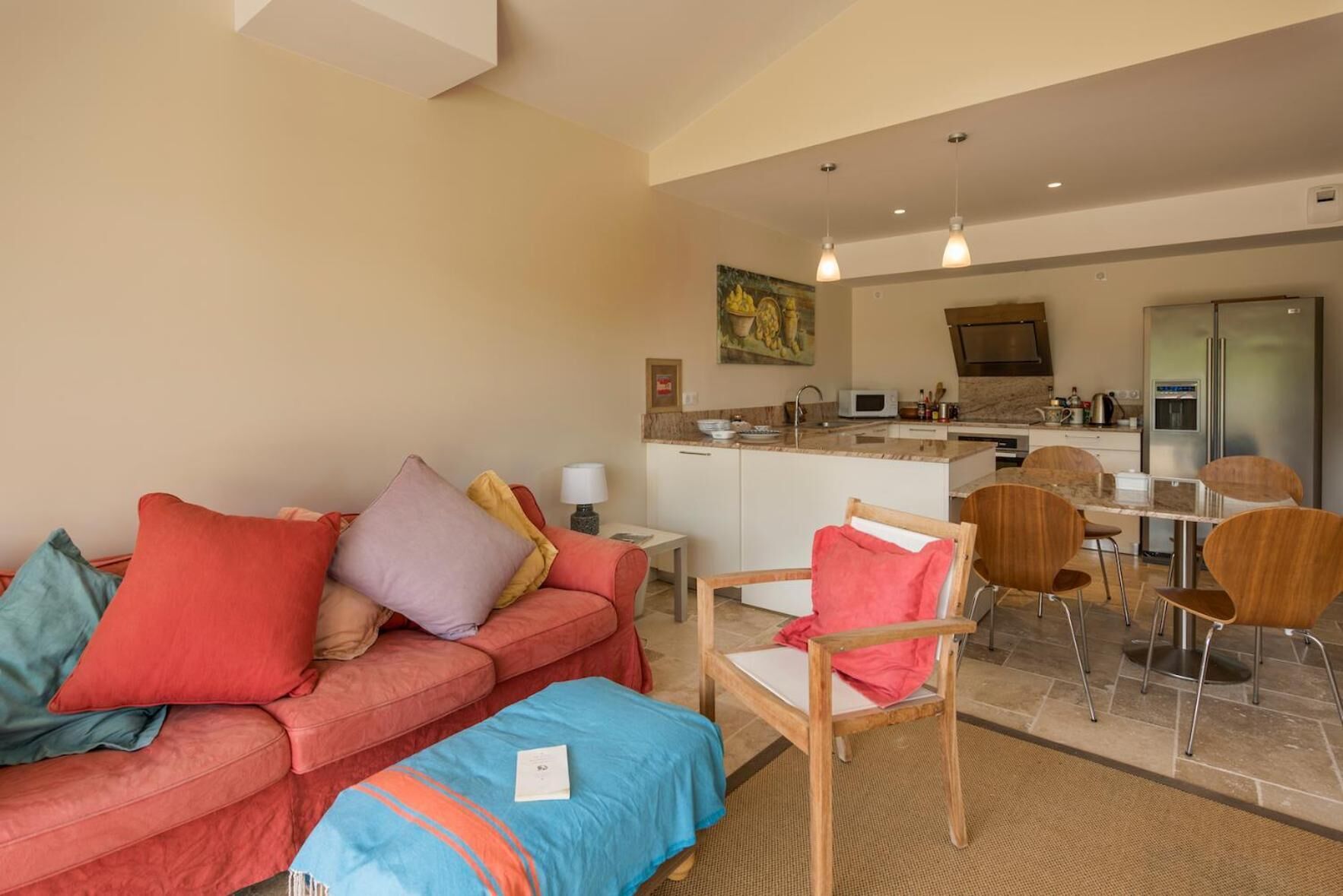 A modern living room with a red sofa, a wooden chair, and a kitchen area with a dining table and chairs.