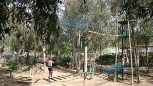Un parque infantil con estructuras para escalar y suelo de arena.