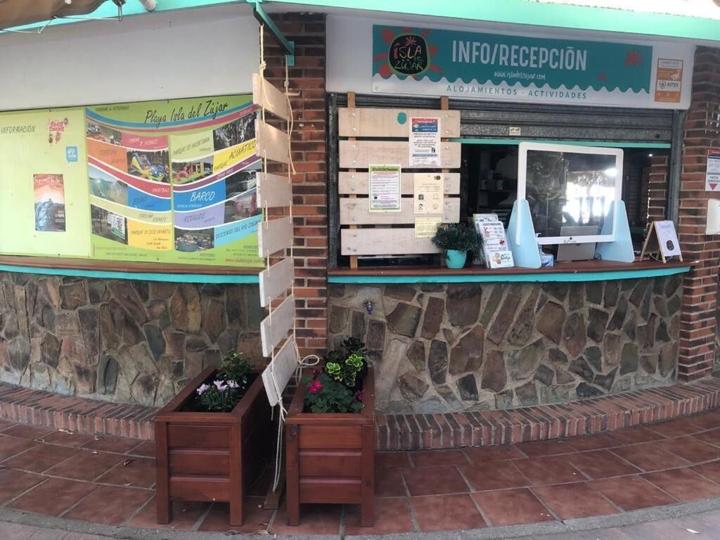 Un edificio con fachada de piedra, una barra de madera con un cartel y un póster en la pared.
