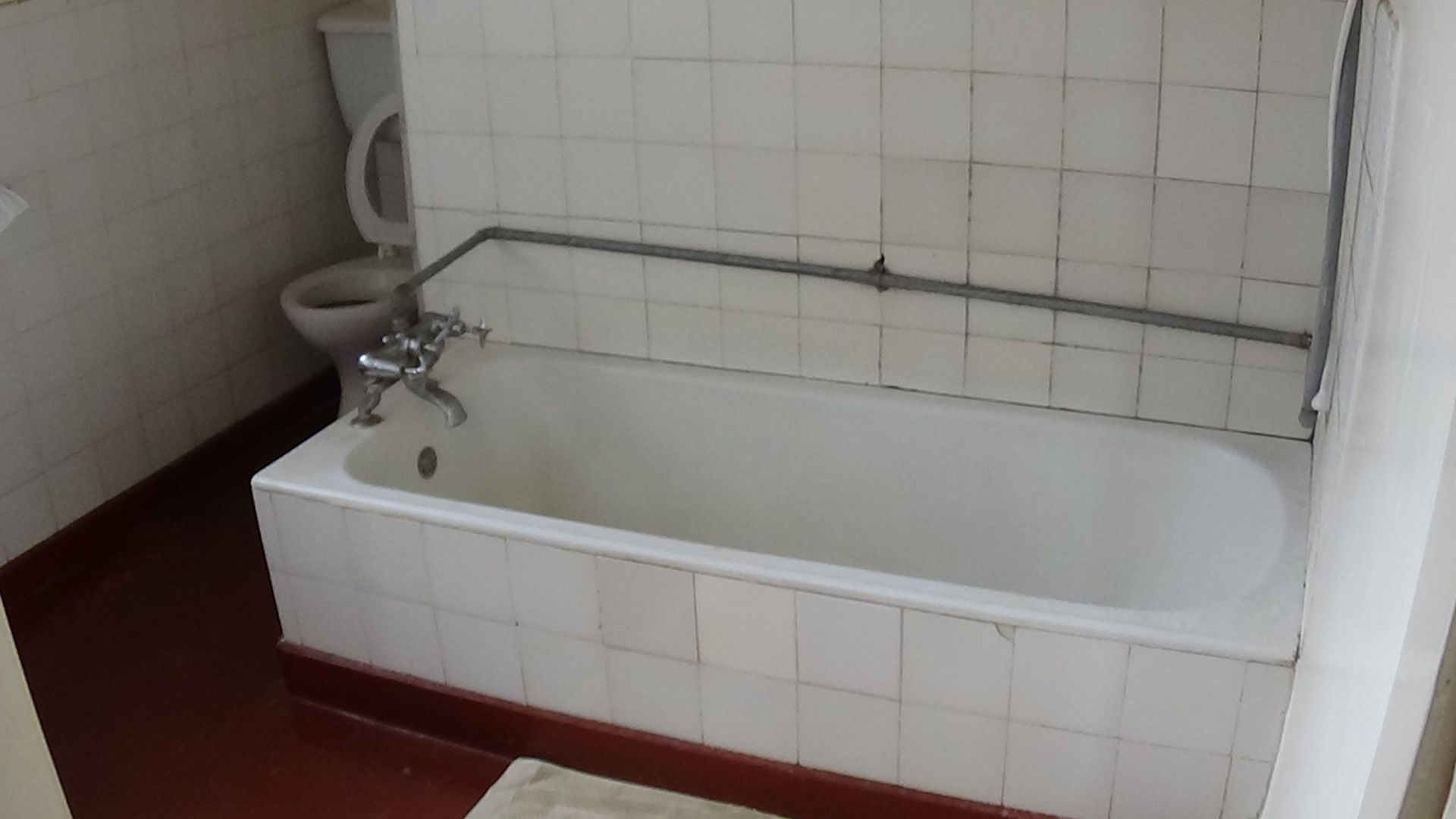 A bathroom with a bathtub, toilet, and a tiled wall.