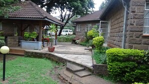 A courtyard with stone buildings, a paved walkway, and potted plants. - Kolping Guest House (Nairobi)