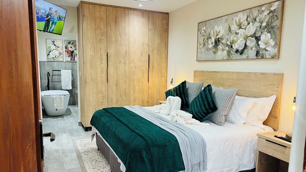 A bedroom with a bed, nightstand, and a TV mounted on the wall.