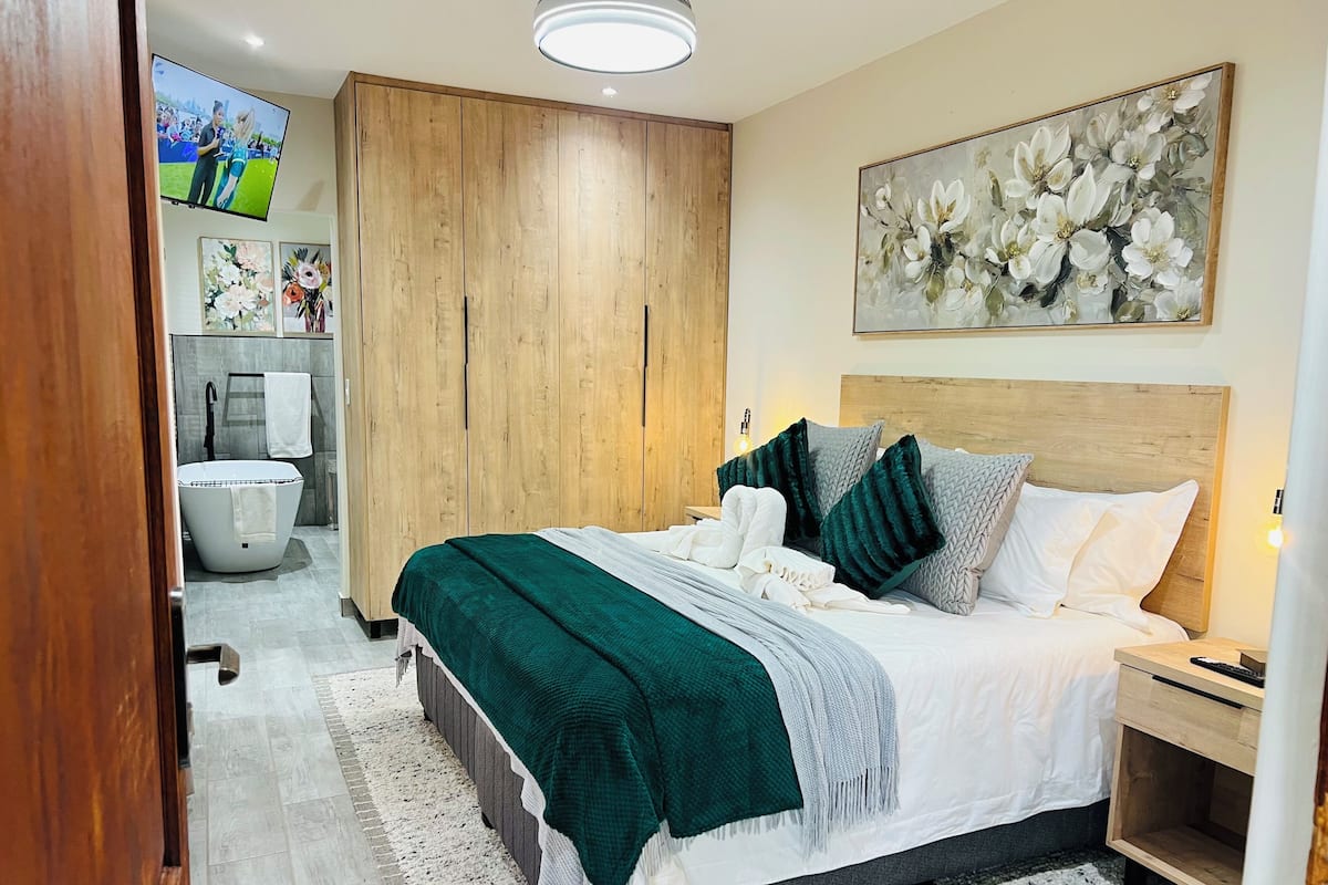 A bedroom with a bed, nightstand, and a TV mounted on the wall.