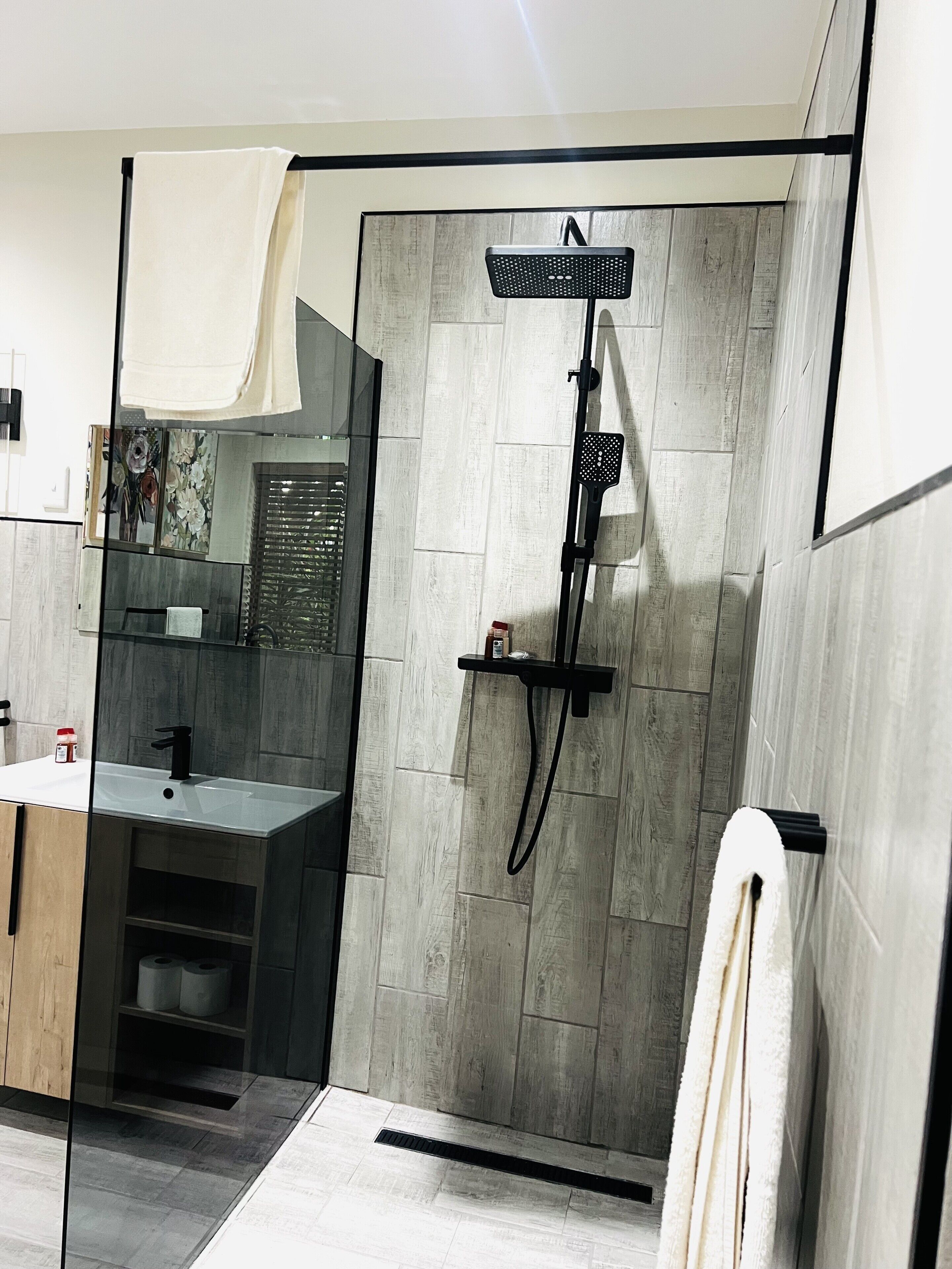 Un baño moderno con cabina de ducha de vidrio, un lavabo y un espejo.