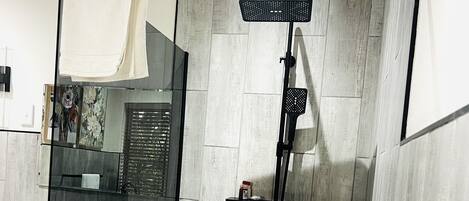 Un baño moderno con cabina de ducha de vidrio, un lavabo y un espejo.
