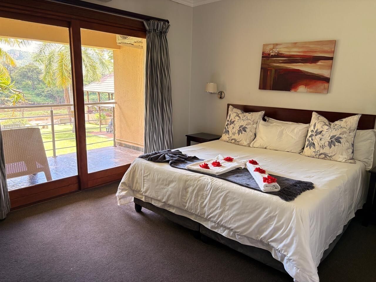 Habitación de hotel con cama, un cuadro y vistas de un jardín a través de una puerta corredera.