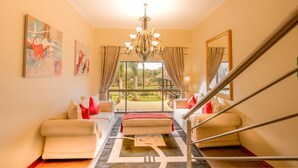 A hotel room with a large window, a chandelier, and artwork on the walls.