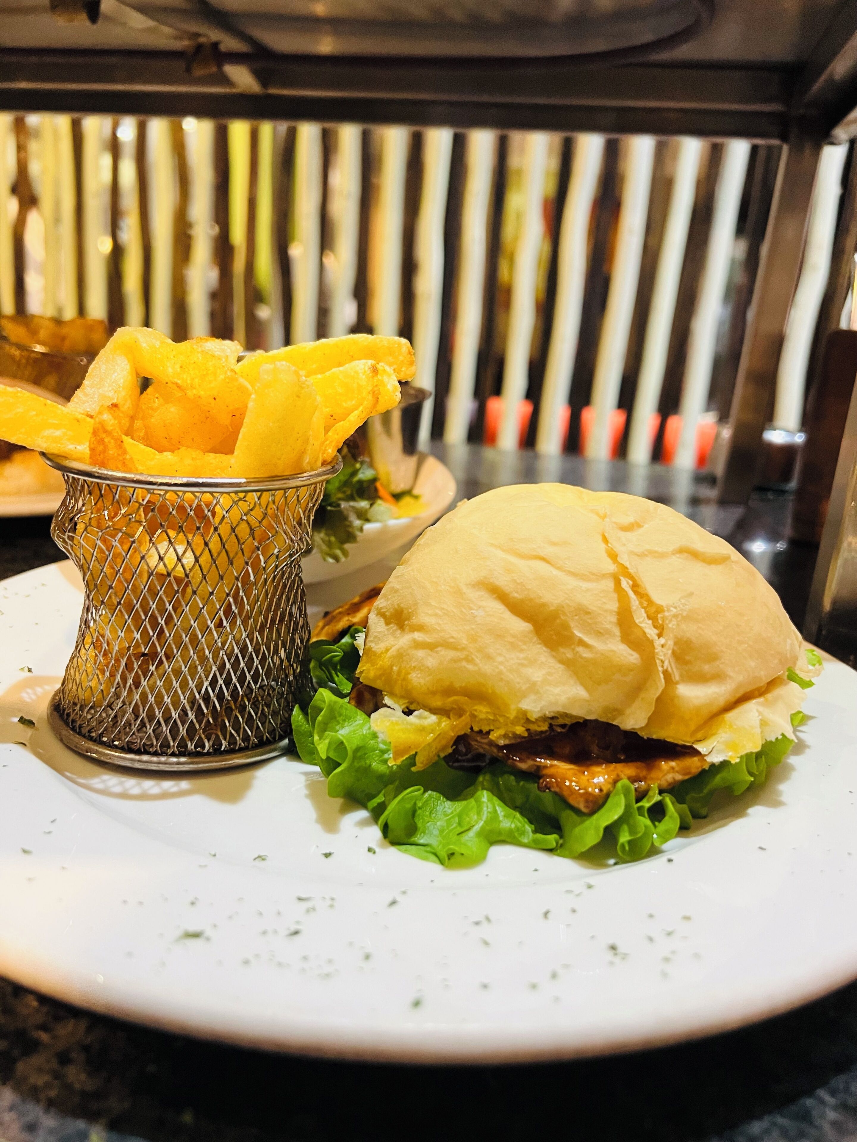 A plate with a sandwich and a basket of fries.