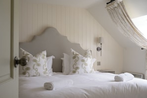 A neatly made bed with pillows, a bedside lamp, and a window with curtains. - Cardross Estate Holiday Cottages (Stirling)