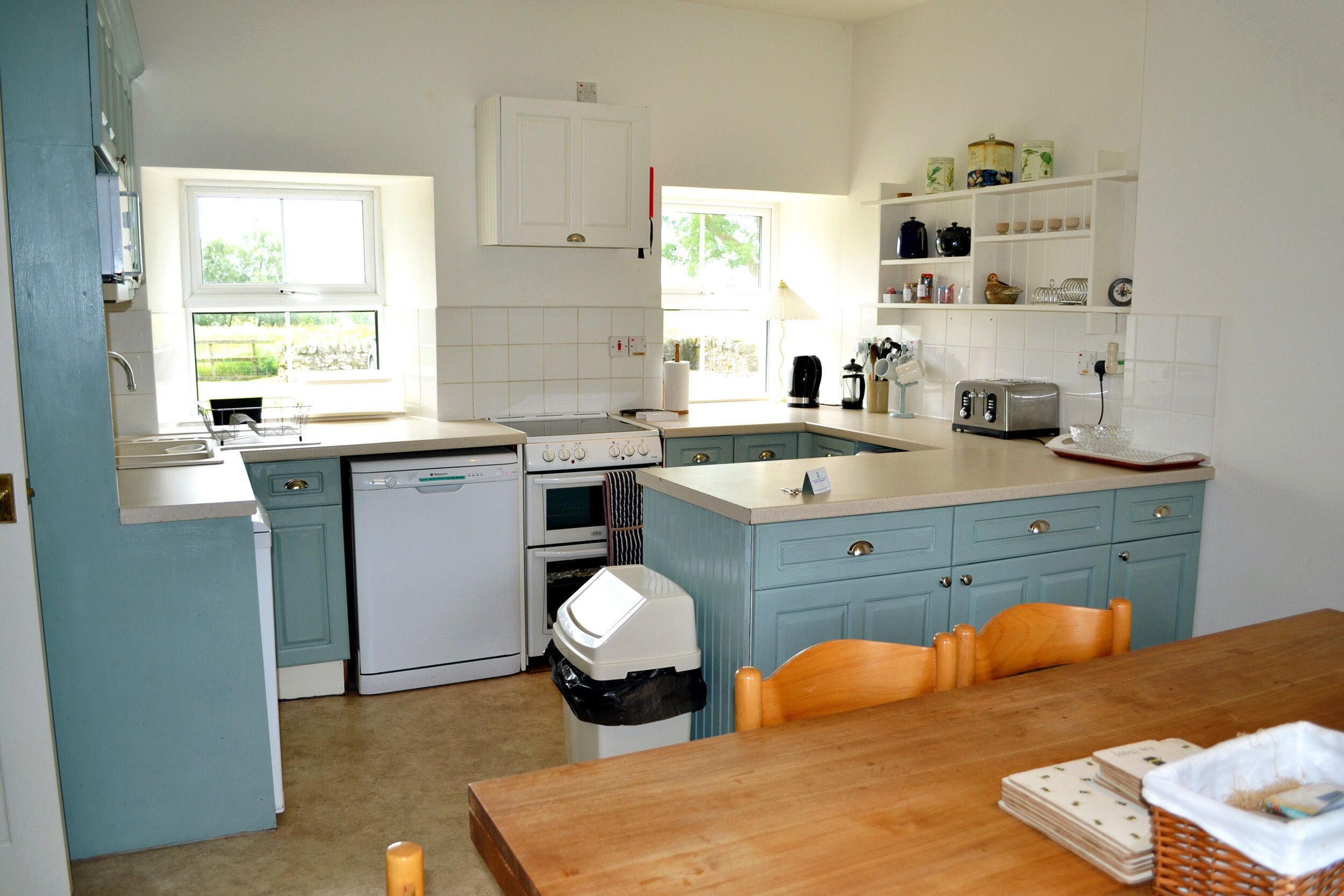 A kitchen with a wooden table, a dishwasher, an oven, and a window.
