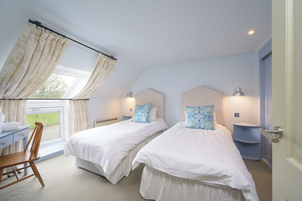 A bedroom with two beds, a desk, and a chair.