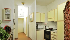 A kitchen with white cabinets, a stove, and a clock on the wall. - Ca Maurice (Venice)
