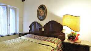 A bedroom with a bed, a nightstand, a lamp, a framed picture on the wall, and a window. - Ca Maurice (Venice)