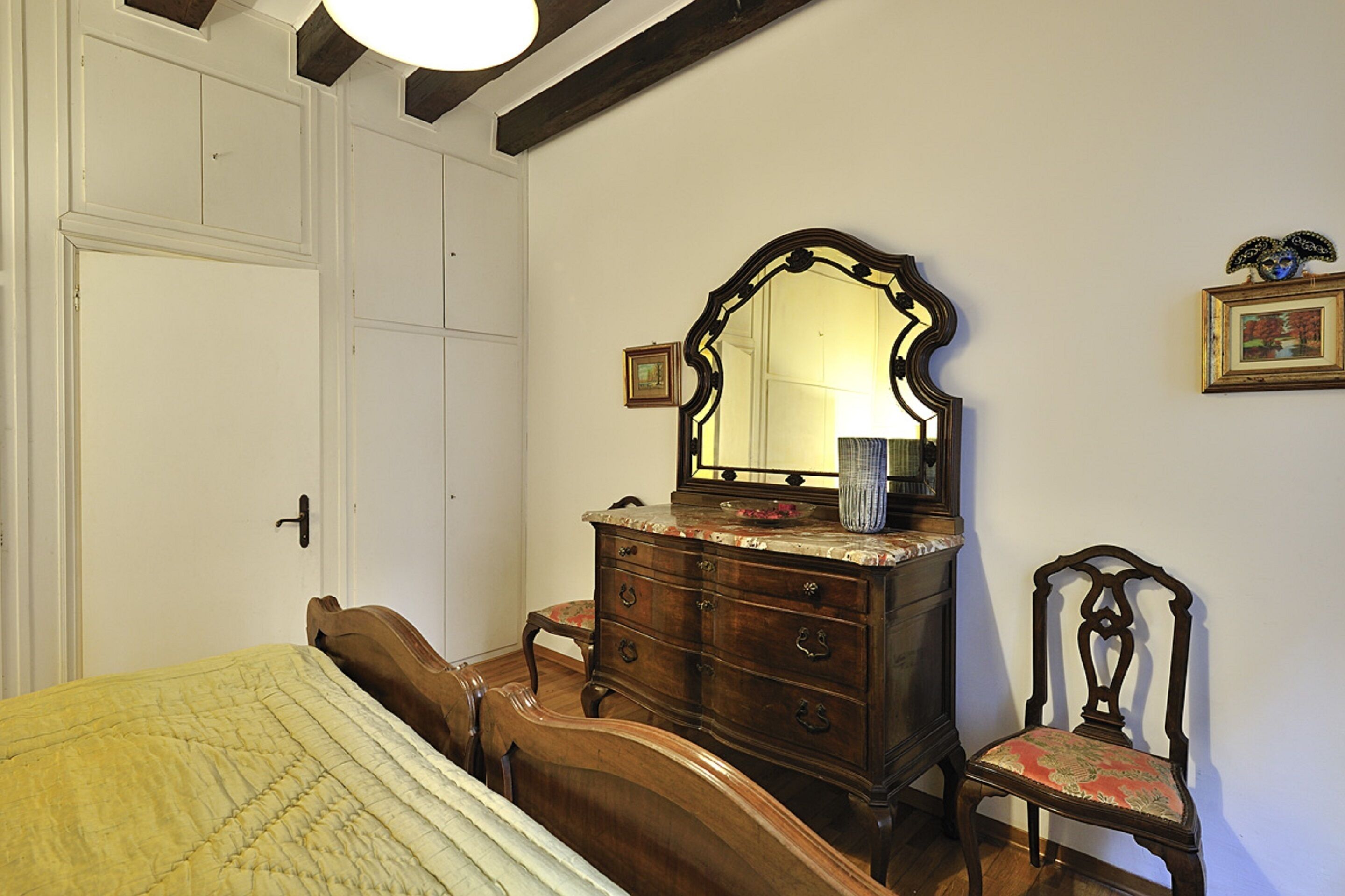 A bedroom with a bed, a dresser, a chair, and a mirror.