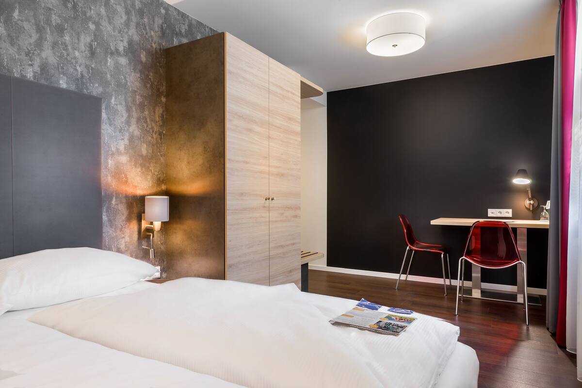 Een hotelkamer met een bed, een bureau, twee stoelen en een muur met een structureel ontwerp.