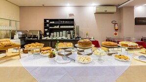 Disposición de bufé con diferentes opciones de comida y una estación de café al fondo.