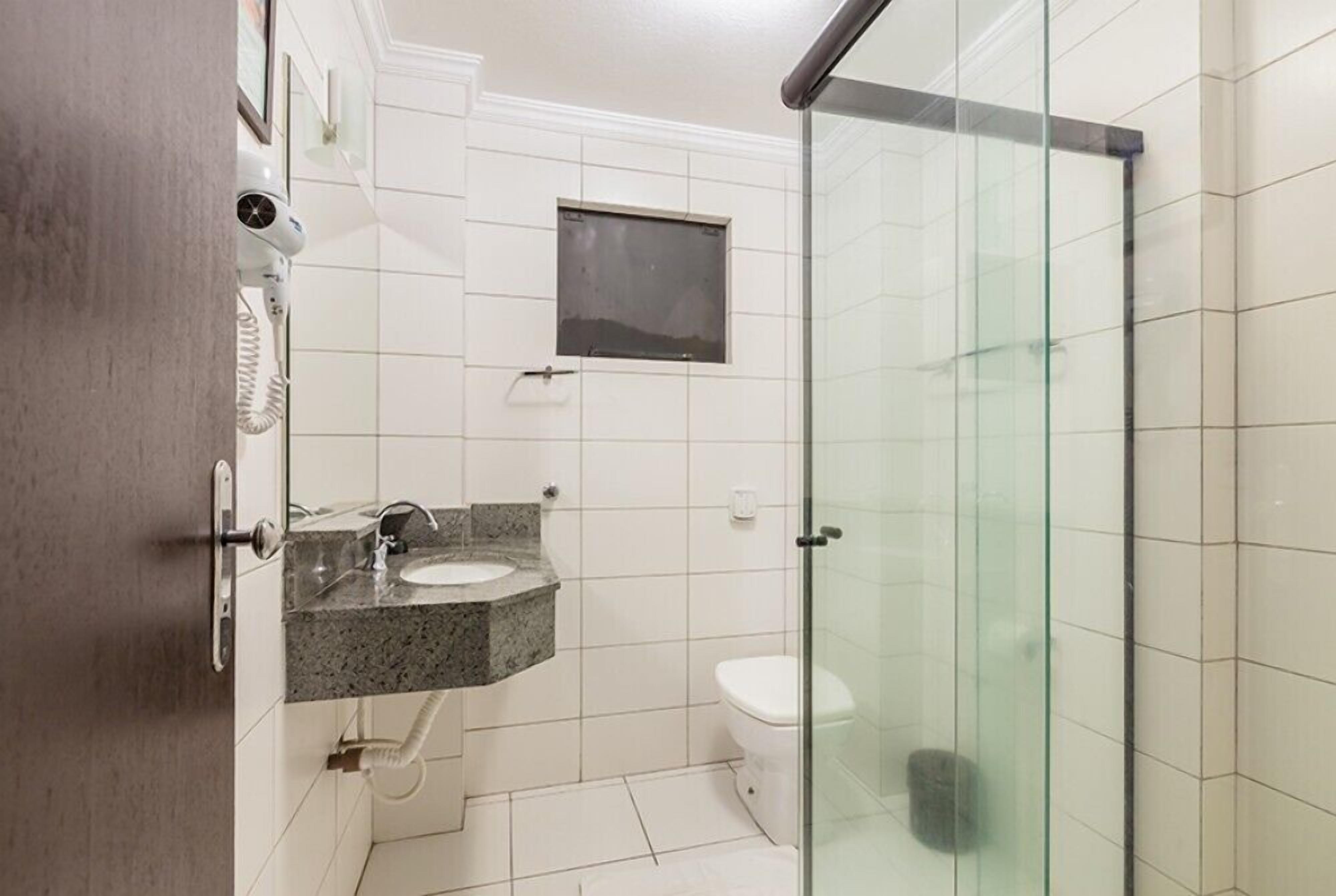 Une salle de bain avec une douche à parois de verre, un lavabo en marbre et des toilettes.