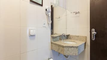 Casa de banho com lavatório duplo, secador de cabelo, toalheiro e dispensador de papel higiénico.