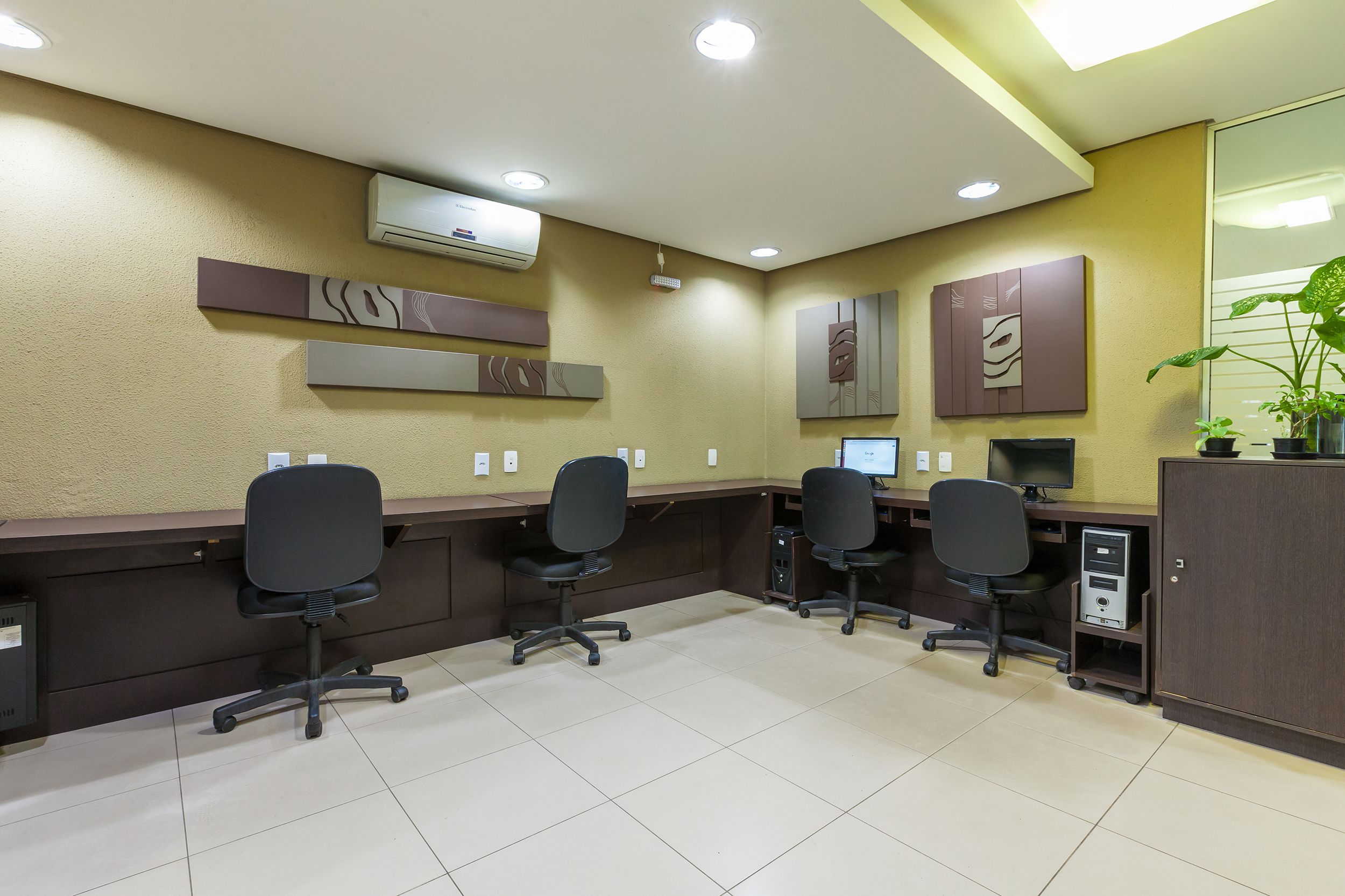 A reception area with a desk, chairs, an air conditioning unit, and a computer.