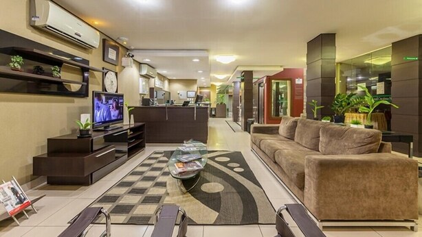 Un moderno vestíbulo de hotel con un sofá, televisor y una mesita de centro.