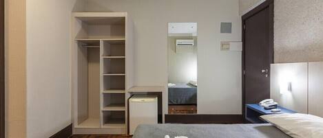 A hotel room with a bed, a wardrobe, a desk, and a mirror.