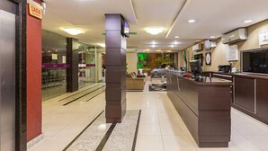 Un hall de hotel con una recepción, una máquina de café y un área de descanso.