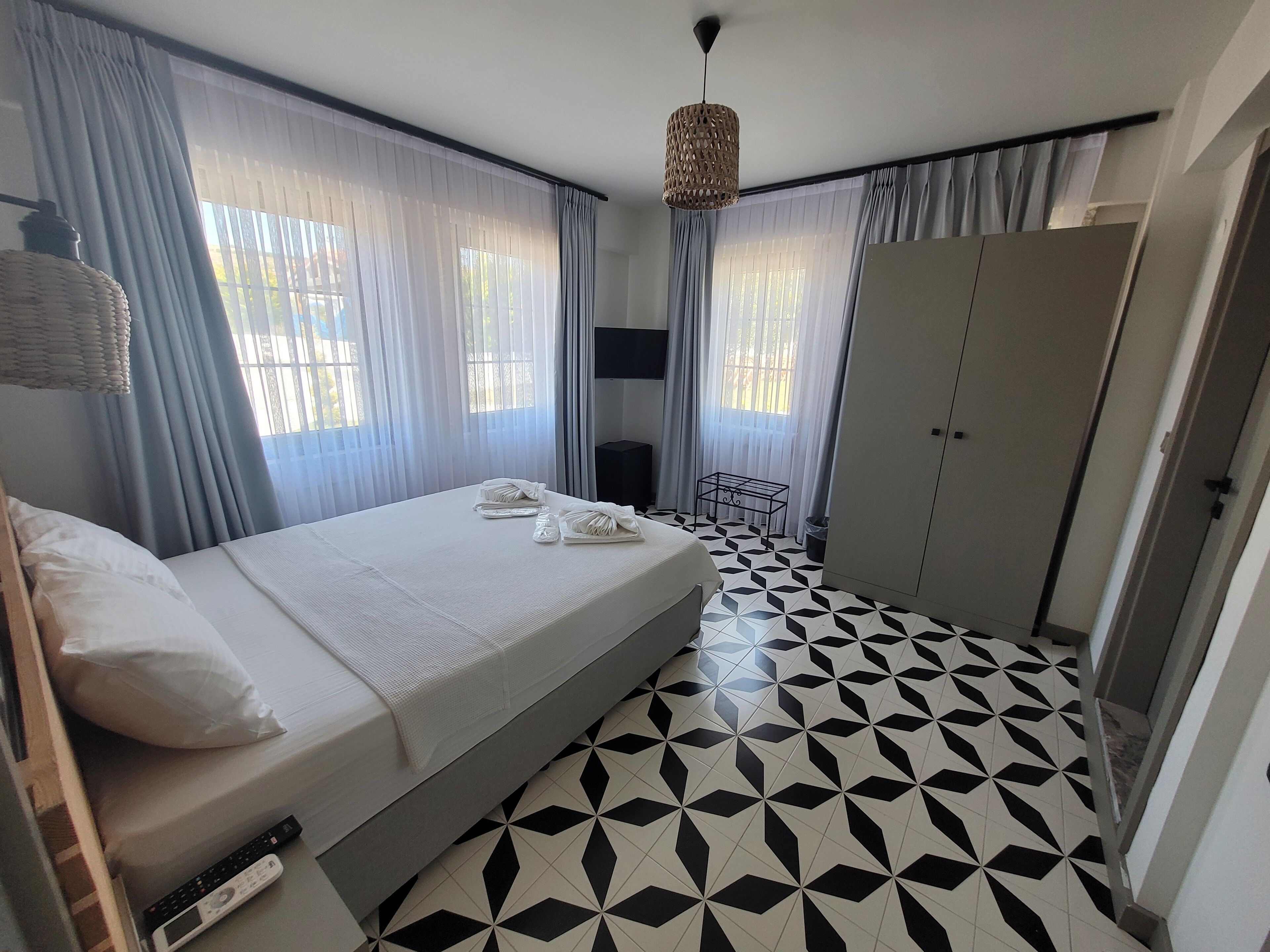 A hotel room with a bed, a TV, a wardrobe, and a patterned floor.