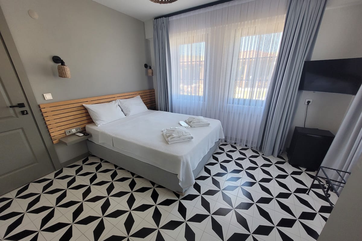 Una habitación de hotel con una cama, una mesita de noche, una lámpara y un televisor.