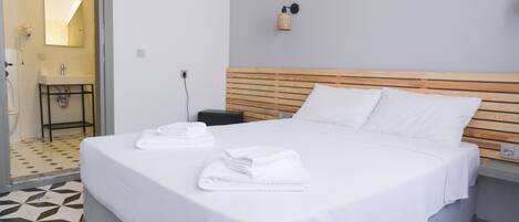 A neatly made bed with white linens, a wooden headboard, and a small bedside table with a lamp.