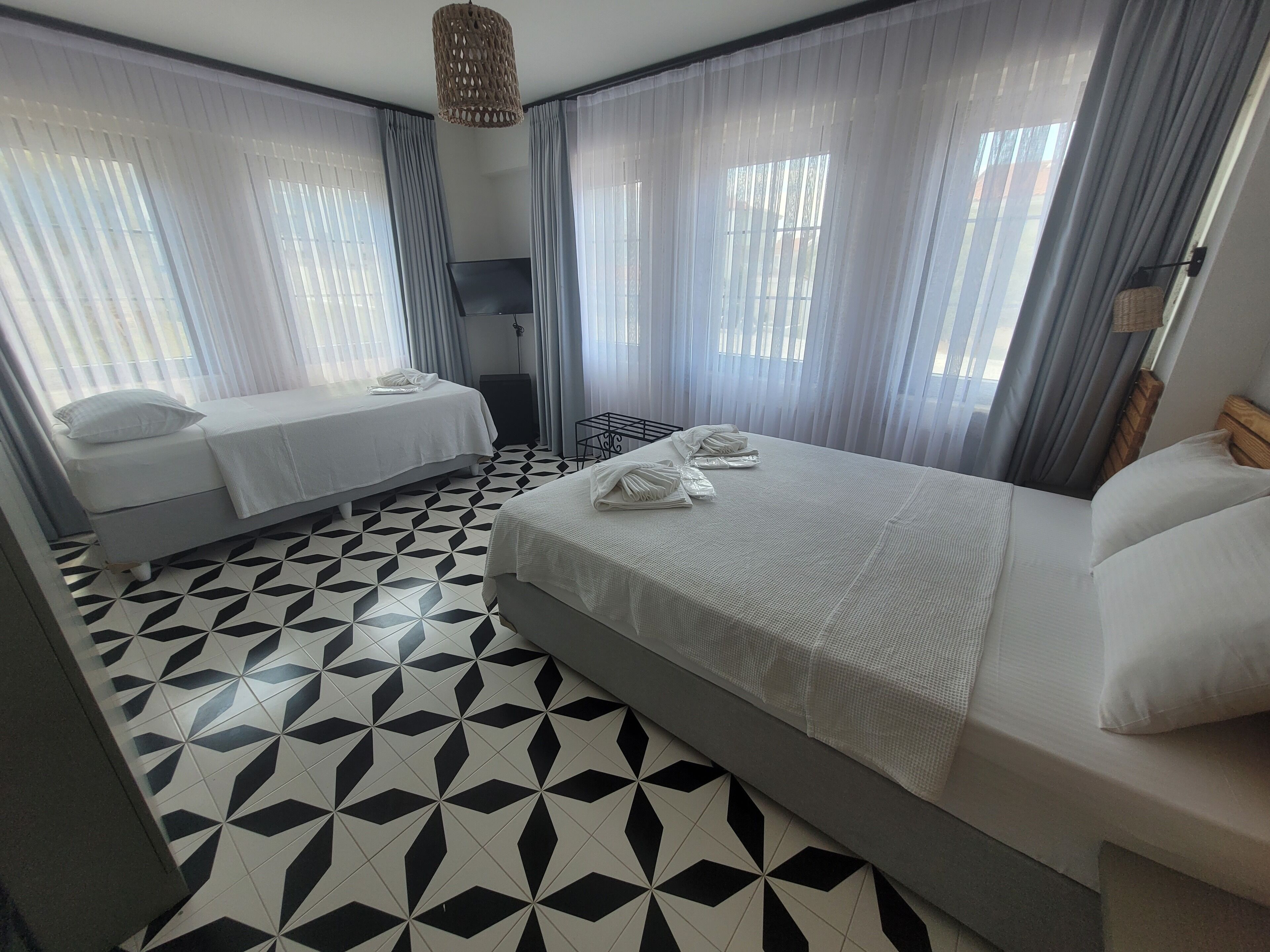 A hotel room with a large bed, a smaller bed, and a desk with a chair.
