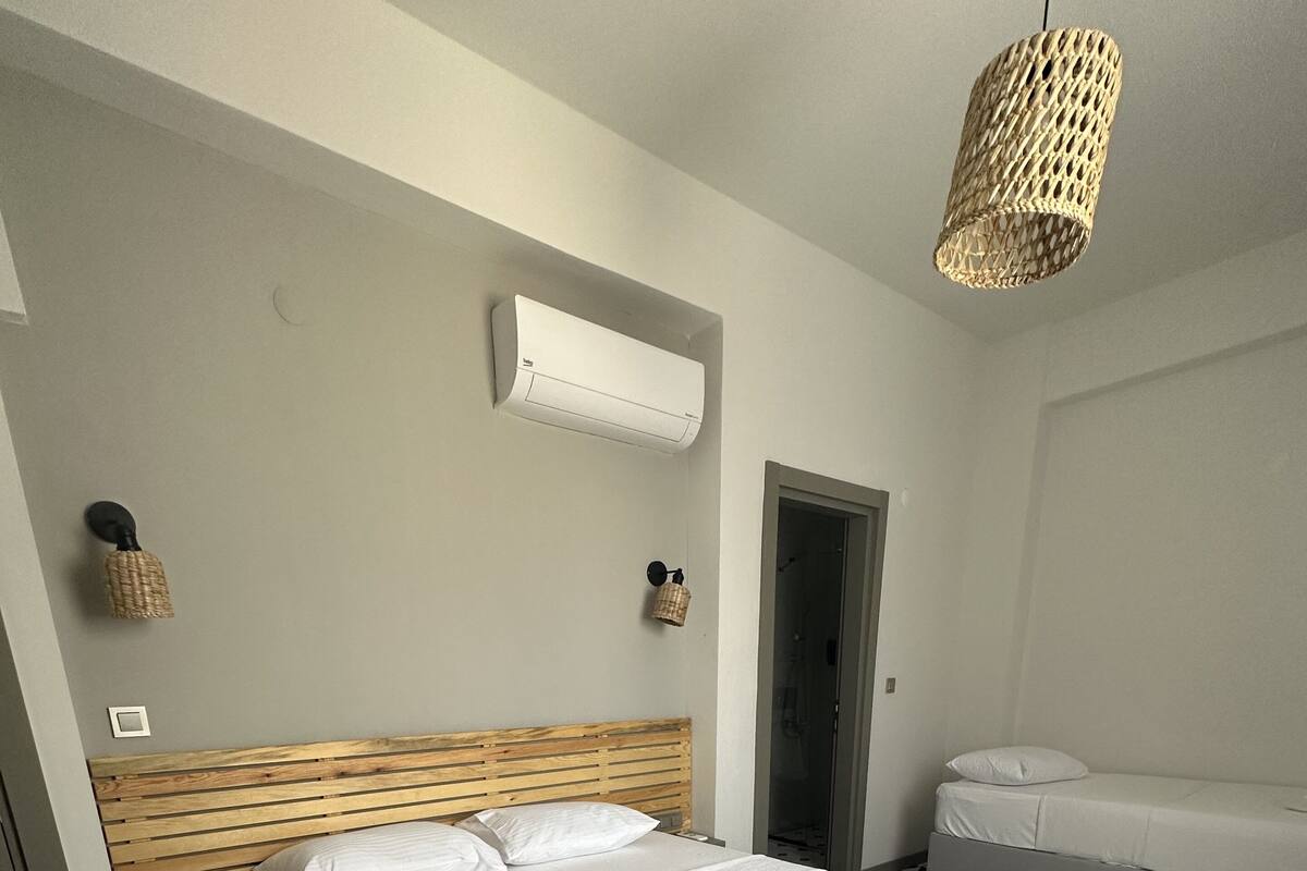 Una habitación de hotel moderna con una cama grande, un pequeño sofá, aire acondicionado de pared y suelo con estampado geométrico.