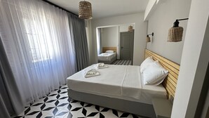 A hotel room with a bed, a bedside table, a mirror, and a patterned floor. - Bozcaada Arcadia (Bozcaada)