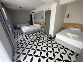 Habitación de hotel con piso de diseño geométrico, dos camas, cabecera de madera, unidad de aire acondicionado y un pequeño cesto de basura.