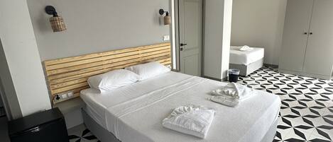 A hotel room with a bed, a small bedside table, a wardrobe, and a bathroom visible through an open door.
