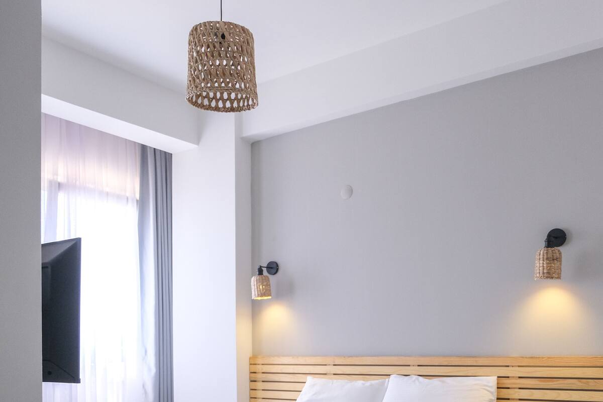 Una habitación de hotel moderna con una cama bien hecha, un televisor de pantalla plana montado en la pared y un suelo con estampado geométrico.