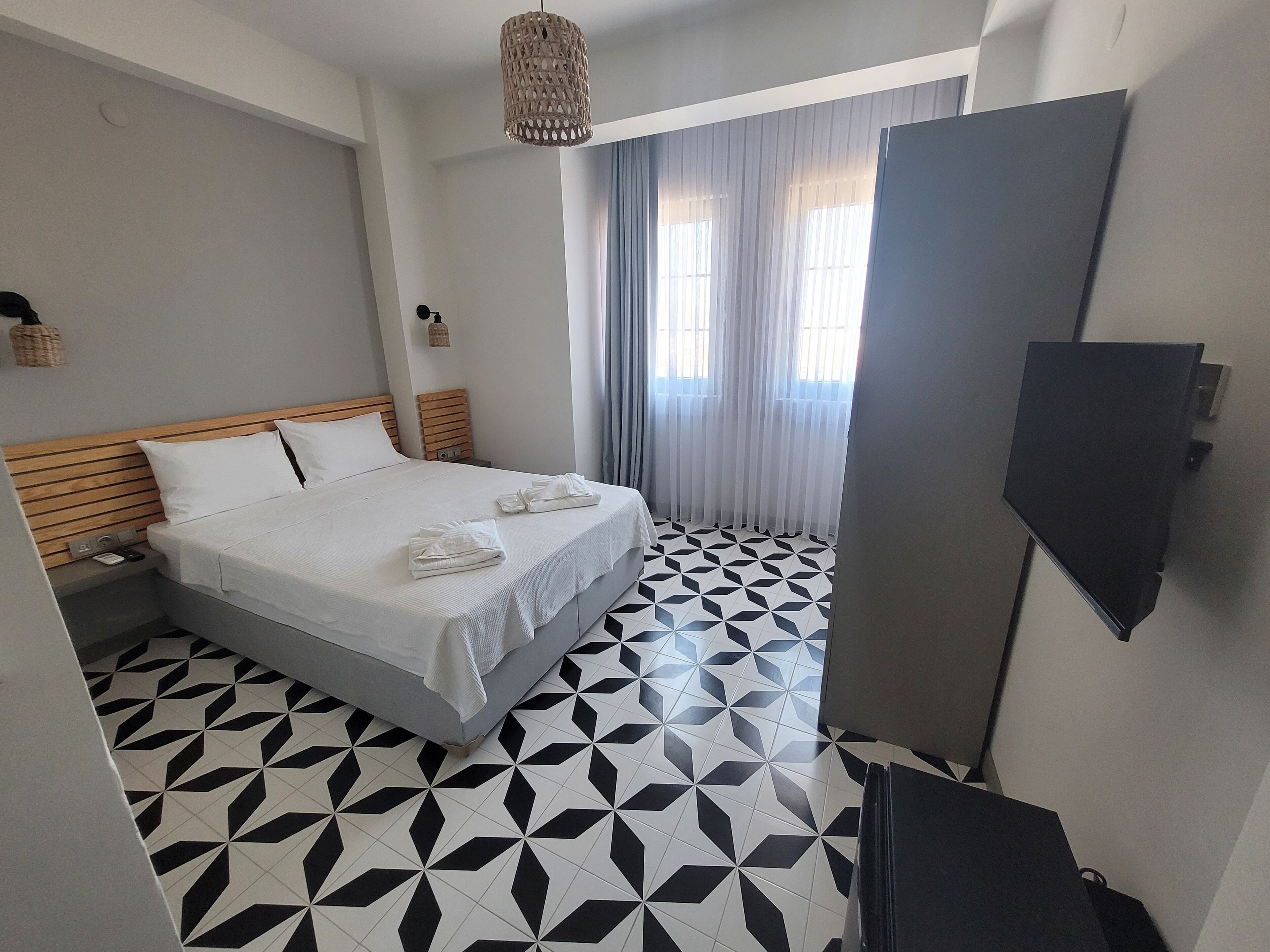 A hotel room with a bed, a TV, and a geometric patterned floor.