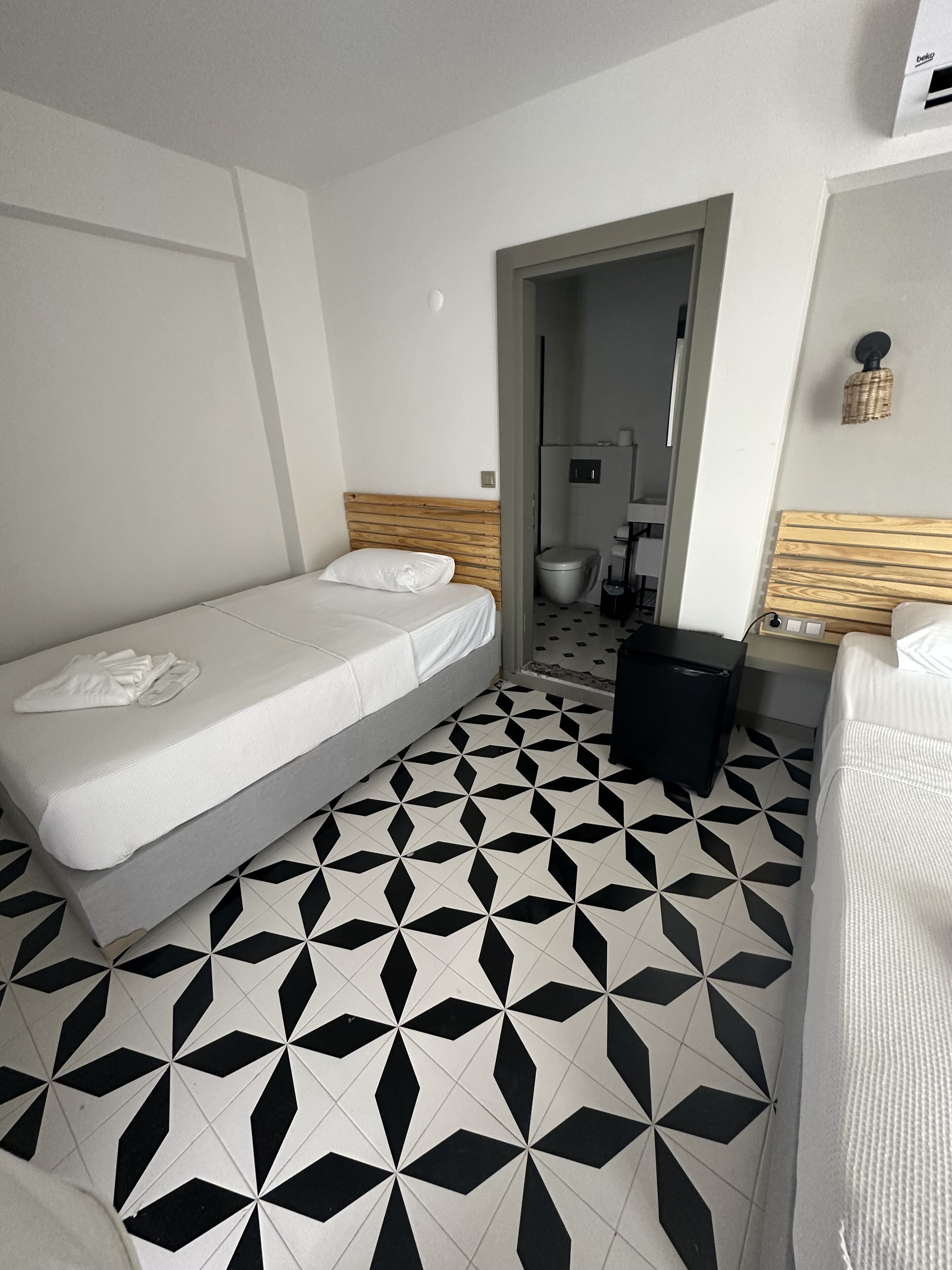 Quarto de hotel com duas camas, banheiro e uma pequena escrivaninha.