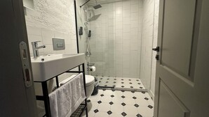 A bathroom with a white sink, toilet, and shower. The floor has a black and white diamond pattern. - Bozcaada Arcadia (Bozcaada)