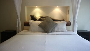 Cama com cabeceira, roupa de cama branca e almofada estampada.